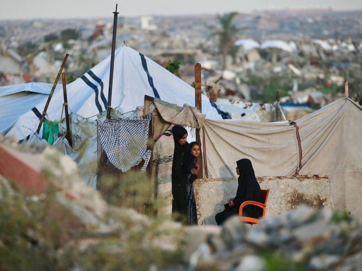 Mujeres palestinas charlan fuera de un refugio improvisado en el campo de refugiados de Nuseirat, en el centro de la Franja de Gaza.