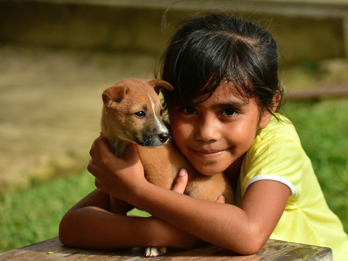 niña sonriente abraza cachorro 