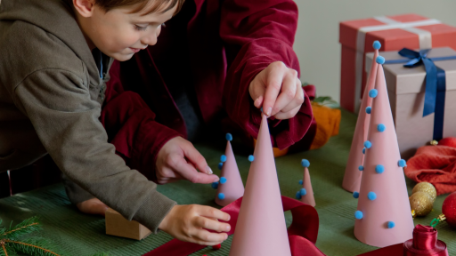 Niño realizando un árbol de navidad creativo y sostenible con su acudiente.  