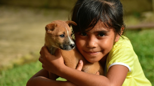 niña sonriente abraza cachorro 